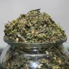 Pile of chopped cannabis leaves and buds on a glass jar, with a Kush Buddy watermark in the corner.