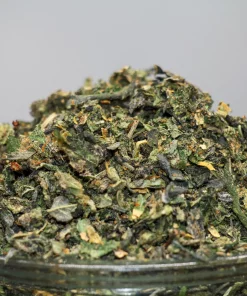 Close-up of a cannabis bud in a glass jar, showing green leaves, orange hairs, and frosty trichomes; Kush Buddy logo in the corner.