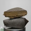 Close-up of a stack of dark brown stones balanced on a small metal pedestal against a gray background.