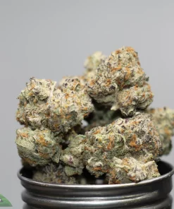 Close-up of frosty cannabis buds stacked in a metal grinder, with the Kush Buddy logo in the bottom-left corner.