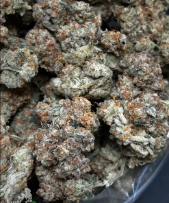 Close-up of sticky cannabis buds with frosty trichomes and orange hairs in a clear bag. Logo bottom-left reads Kush Buddy.