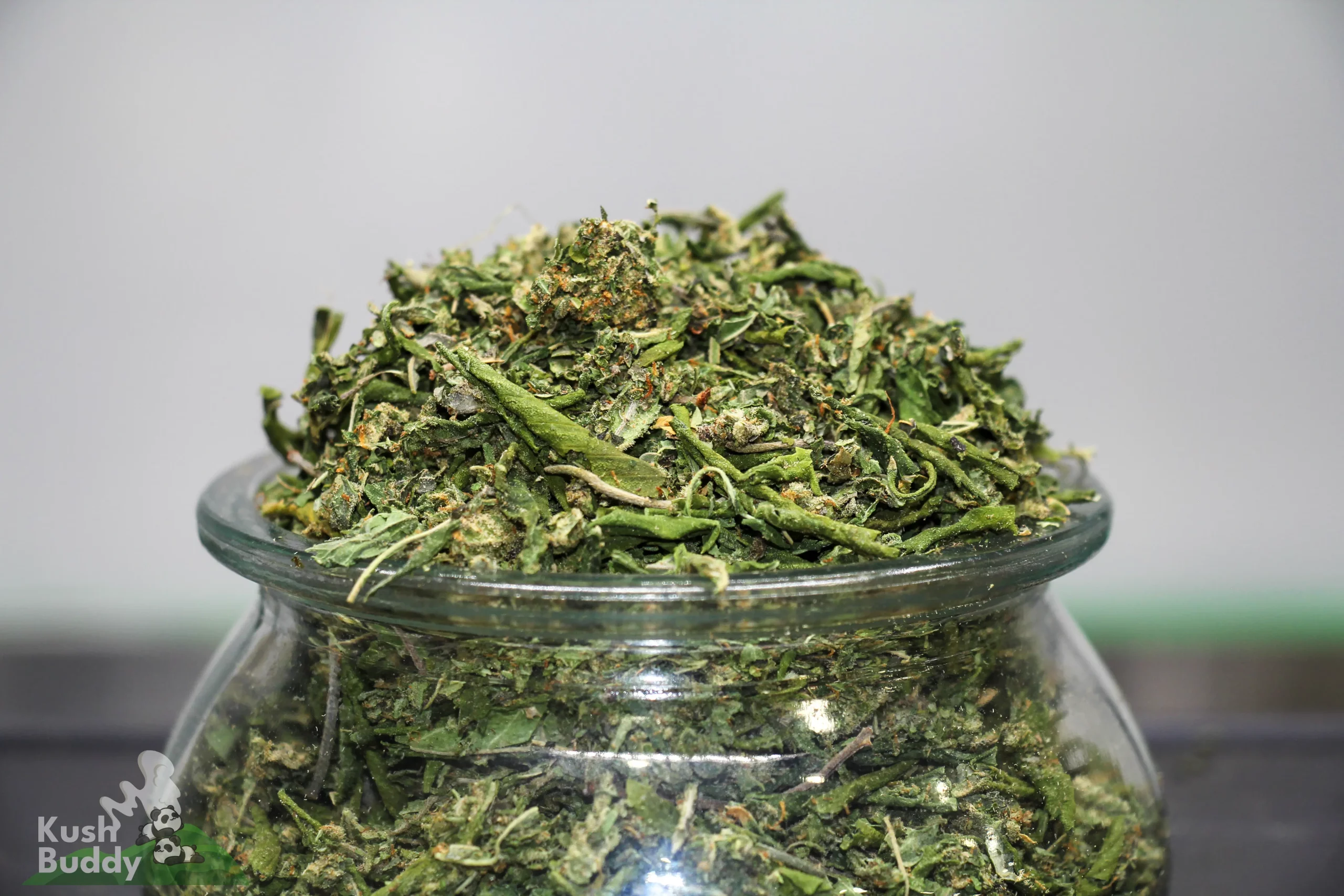 Crushed cannabis buds piled high in a glass jar.