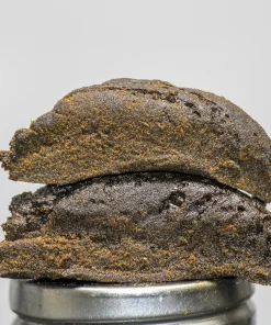 Stack of dark, glossy chocolate cookies piled on a metal ring, with a Kush Buddy watermark in the bottom-left corner.