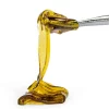 Golden honey oil concentrate shown on a metal pick – representative image